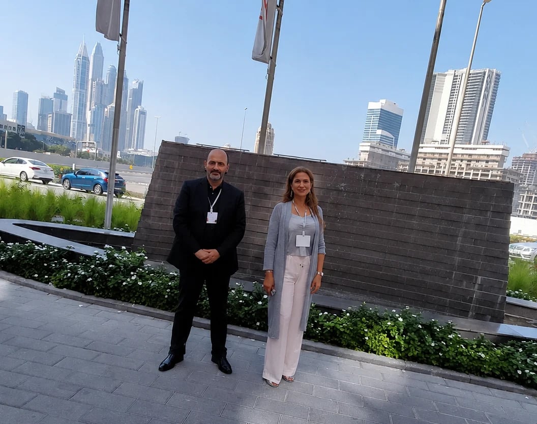 Two professionals wearing ID badges stand on a rooftop with a city skyline in the background