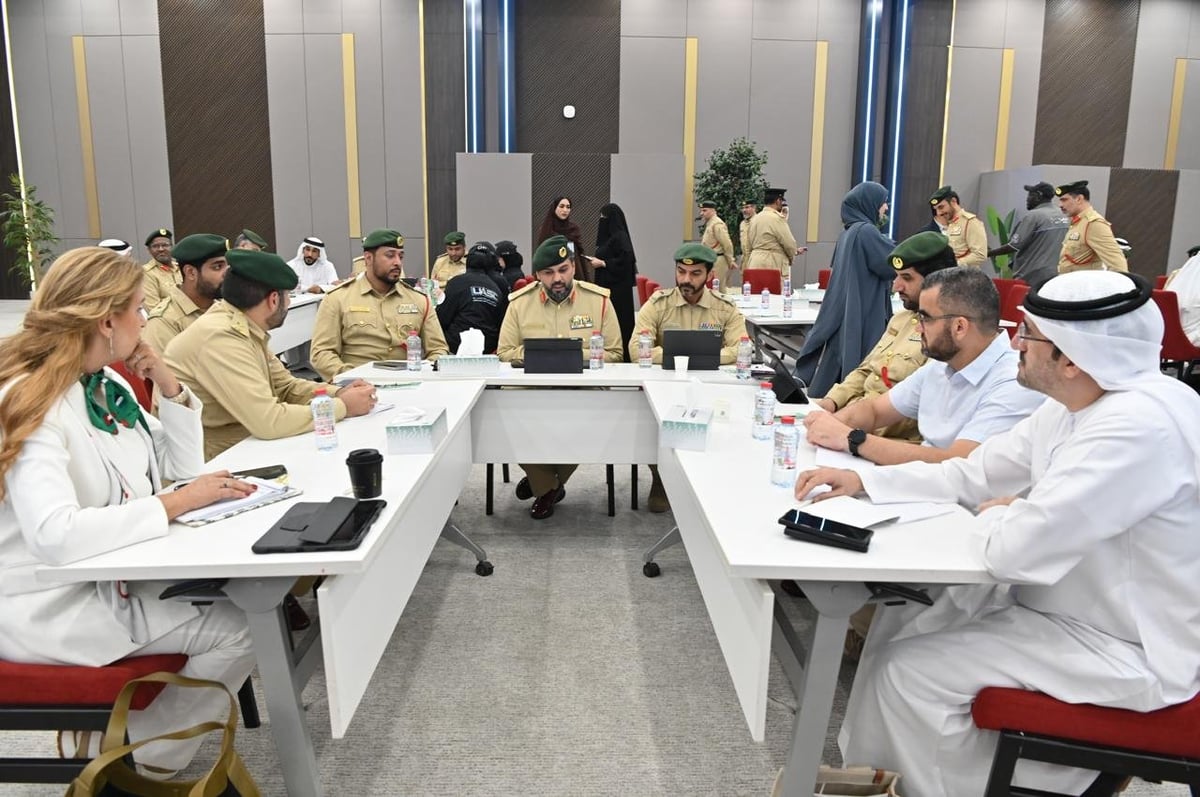 Business meeting in a modern conference room with diverse professionals seated at a long white table, some wearing traditional Middle Eastern attire